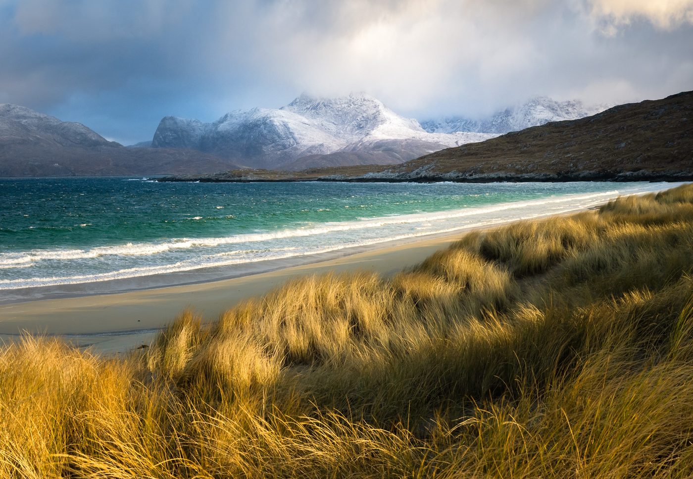 Golden dune grass, turquoise sea and snowy mountains on Harris